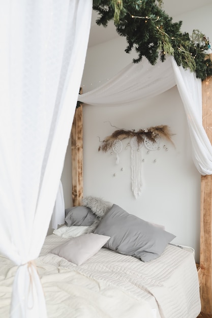 Interior moderno do quarto em estilo escandinavo com uma cama aconchegante com dossel de madeira e travesseiros