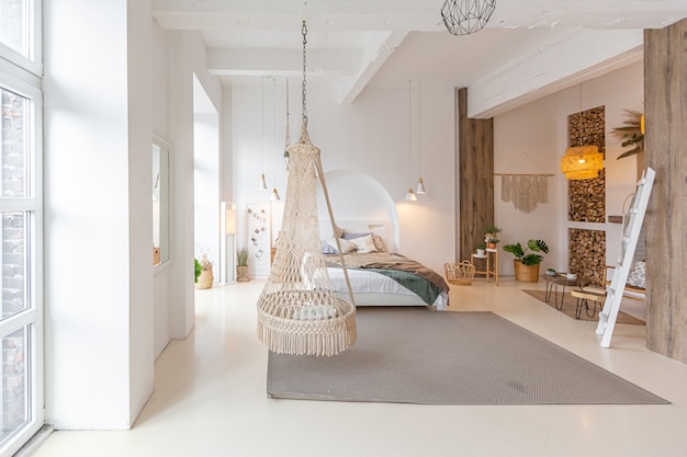 Interior moderno e elegante de um apartamento estúdio leve com colunas de madeira no estilo loft, decorado com tijolos, mármore e madeira com móveis elegantes e paredes brancas