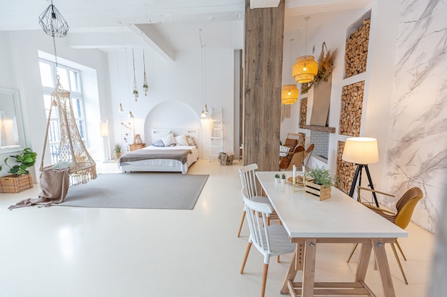 Interior moderno e elegante de um apartamento estúdio leve com colunas de madeira no estilo loft, decorado com tijolos, mármore e madeira com móveis elegantes e paredes brancas