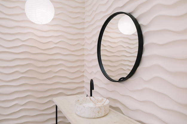 Interior moderno con un elegante espejo redondo junto a una pared beige en una habitación acogedora, espacio para copiar, accesorios elegantes en una elegante decoración del hogar