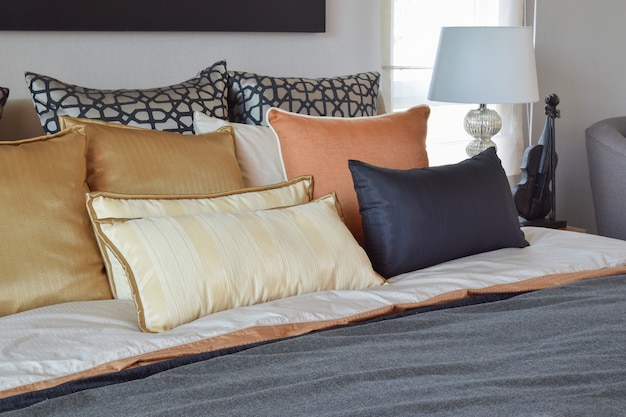 Interior moderno quarto com almofadas de laranja e ouro na cama e mesa de cabeceira