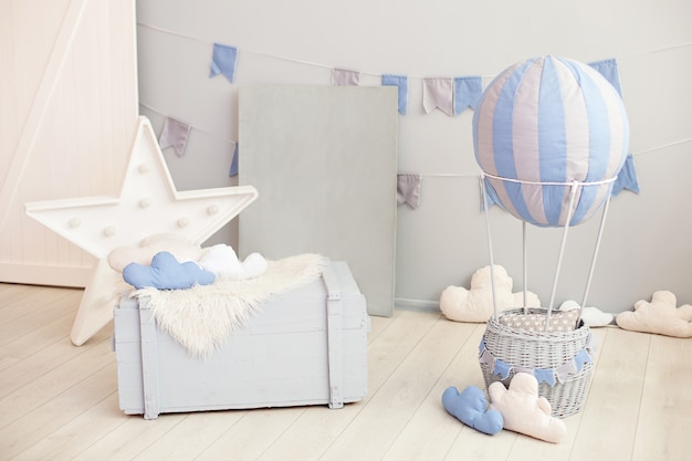 Interior moderno de la sala vintage para niños con una cómoda de madera y un globo con nubes en una pared blanca con banderas festivas. Dormitorio infantil. interior de la guardería. rústico