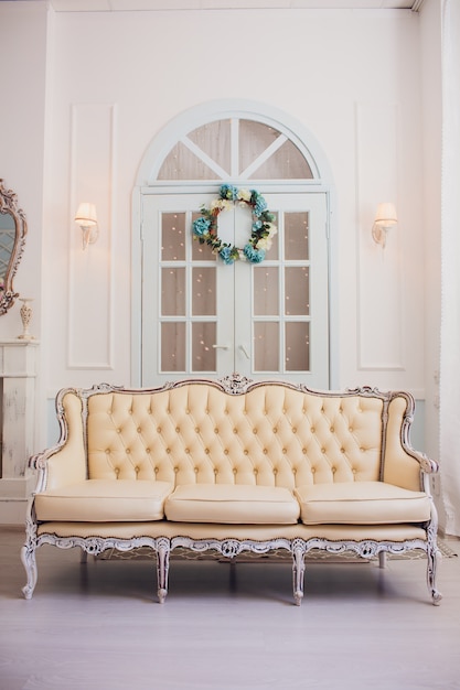 Foto interior con muebles vintage, estudio de primavera ligera con hermoso sofá blanco. interior blanco de estudio.