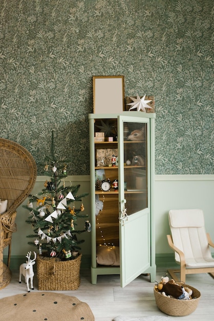 Interior de Navidad de menta escandinava con árbol de Navidad decorado en la habitación de los niños Armario con juguetes para niños silla de mimbre cómoda