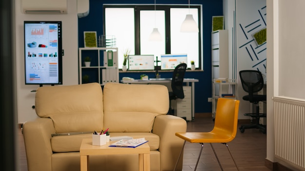 Interior de la oficina moderna de planta abierta sin gente, interior de habitación elegante con mesa, sofá y sillas. Área de descanso en el centro de negocios con sofá pequeño, foto de habitación vacía con muebles modernos.