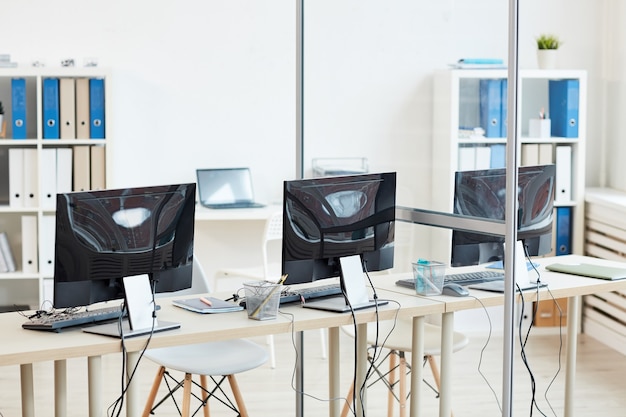 Interior de la oficina vacía con tres escritorios de computadora en fila