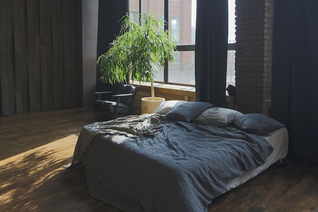 Interior oscuro de un apartamento estudio de estilo loft de planta abierta enorme, moderno y elegante, con columnas y techos altos.