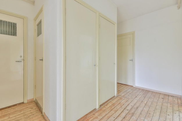 Interior de pasillo blanco con suelo de madera y puertas blancas de estilo antiguo