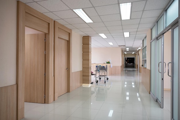 Interior del pasillo del hospital vacío con varias habitaciones y carrito de servicio al paciente en la recepción