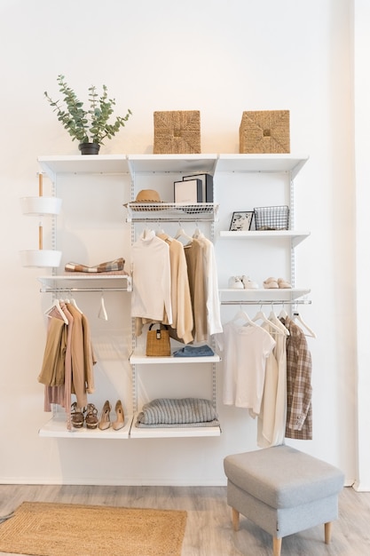 Foto interior de la sala de exposiciones con ropa elegante y accesorios colección de ropa femenina colgada en el perchero en el interior del vestidor con perchero