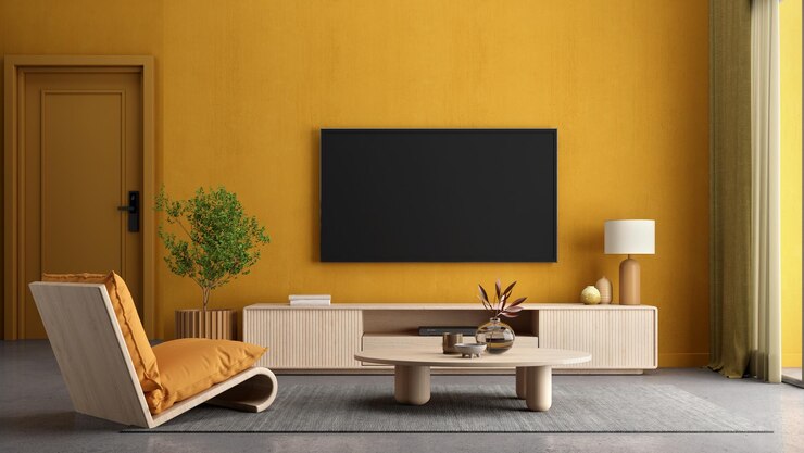 Interior de salón amarillo con sillón TV y planta