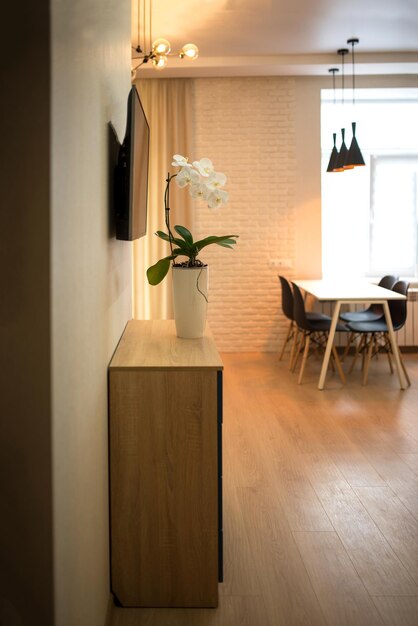 Interior de salón y cocina de planta abierta con armarios blancos, mesa y sillas