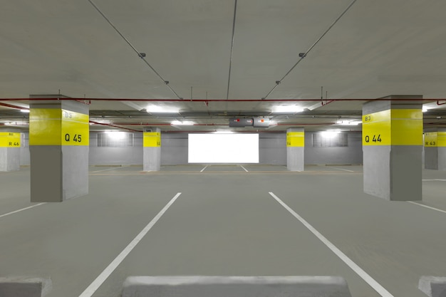 Foto interior subterrâneo da garagem de estacionamento com quadro de avisos em branco.