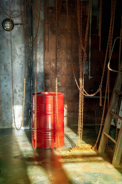 El interior de la tienda industrial de la fábrica con cadenas y un barril rojo está iluminado por la luz del sol desde la ventana