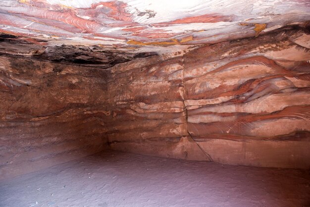 Foto en el interior de una tumba subterránea abandonada en petra jordania tallada en rocas de arenisca estratificadas de colores