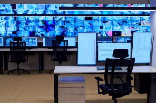 Foto interior vazio da grande sala de controle do sistema de segurança moderno, estação de trabalho com vários monitores, sala de monitoramento com centro de dados de segurança escritório vazio, mesa e cadeiras em um dos principais dados de segurança cctv