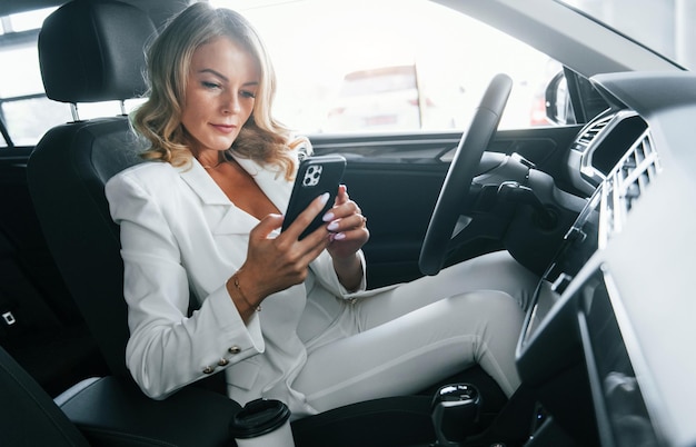 Interior del vehículo Mujer en ropa formal está adentro en el autosalon