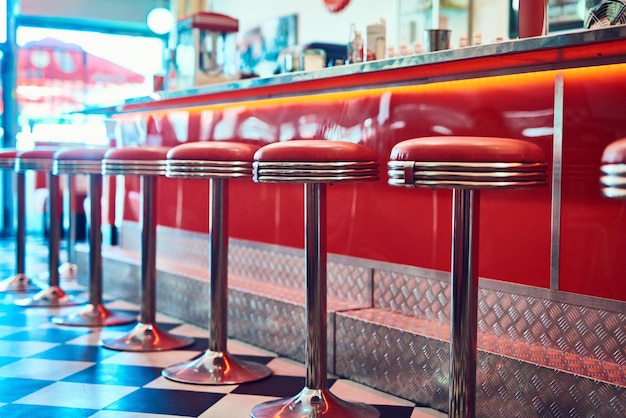 Interior vintage y retro de moda en un restaurante o cafetería con una decoración funky Cabina de la vieja escuela y sillas junto a un mostrador o bar en un café vacío maravilloso, vibrante y elegante a la antigua