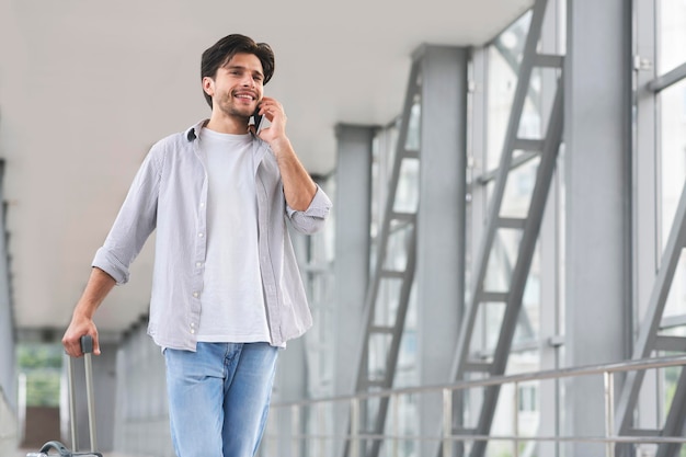 International Roaming junger Mann, der auf dem Handy spricht, während er im Flughafen spazieren geht