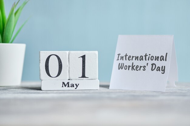 Internationaler Arbeitertag im Urlaub - 1. Kalenderkonzept des ersten Mai-Monats auf Holzblöcken.