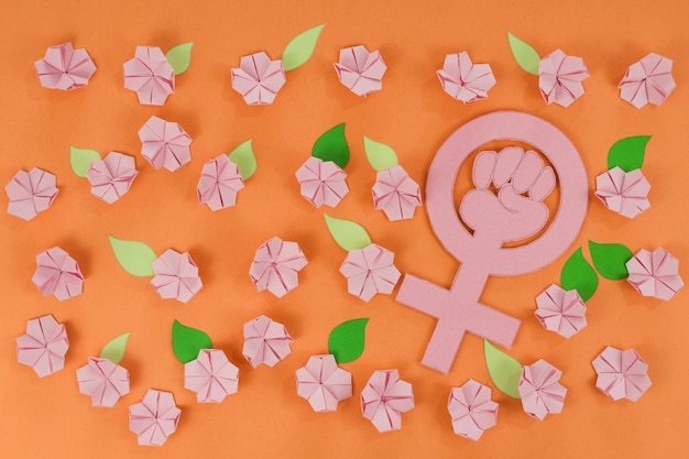 Internationaler Frauentag Rosafarbene Origami-Blumen mit papiergrünen Blättern auf orangefarbenem Hintergrund