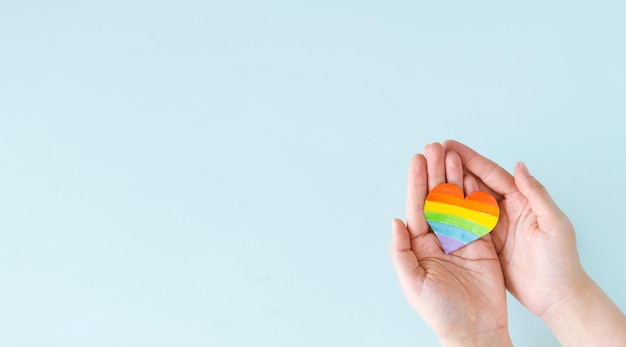 Internationaler Tag gegen Homophobie Transphobie und Biphobie Herz mit Regenbogen-LGBT-Flagge in den Händen