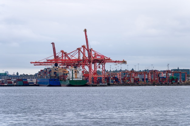 Internationales Frachtschiff mit Containerladung und Portalkränen auf Handelshafen