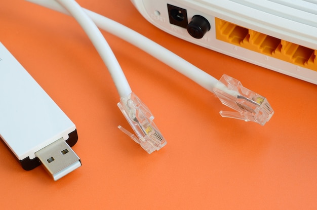 Internet-Router, tragbarer USB-WLAN-Adapter und Internet-Kabelstecker liegen auf einem hellen orangefarbenen Hintergrund. Erforderliche Elemente für die Internetverbindung