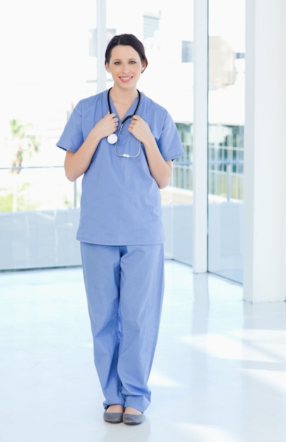 Interno médico sorrindo vestindo um uniforme azul de manga curta