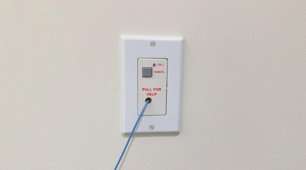 Un interruptor de luz blanca con un cable azul enchufado.