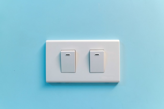 Interruptor de luz blanca contra la pared azul