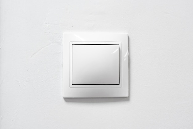 Interruptor de luz blanca en una pared plana diseñado para un fácil acceso y estética moderna en interiores domésticos