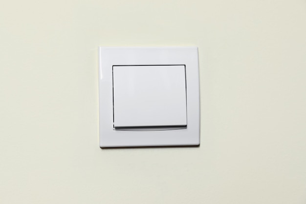 Interruptor de luz de plástico moderno en primer plano de pared blanca