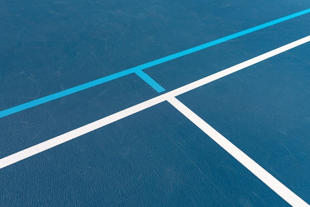 Intersección de canchas de tenis azules con líneas blancas y líneas de pickleball azules claras