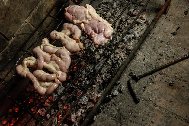 Foto intestinos de vaca presentados en una tabla de madera con ingredientes listos para asar a la parrilla