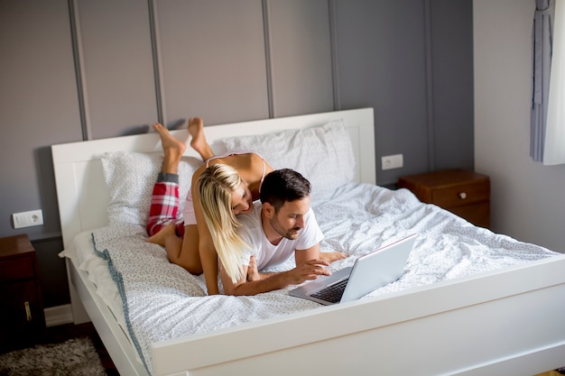 Intime Liebhaber mit Laptop auf dem Bett im Schlafzimmer liegen