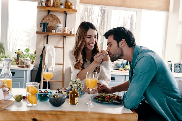 Intime Momente. Schönes junges Paar, das ein gesundes Frühstück genießt, während es zu Hause in der Küche sitzt