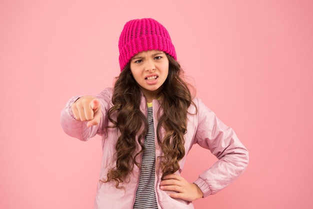 Intimidación y vergüenza Niña ropa de invierno fondo rosa Concepto de infancia Chica emocional cabello largo sombrero de punto Chica adolescente estilo casual Estado de ánimo de las emociones Prevención de la intimidación Señalarte