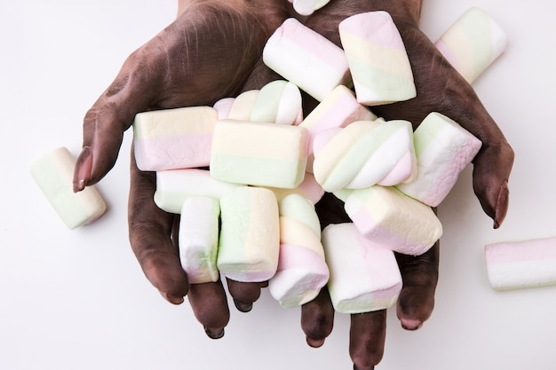 Intoxicação alimentar e má higiene das mãos. mãos sujas segurando marshmallows em fundo branco. conceito de germes e condições insalubres