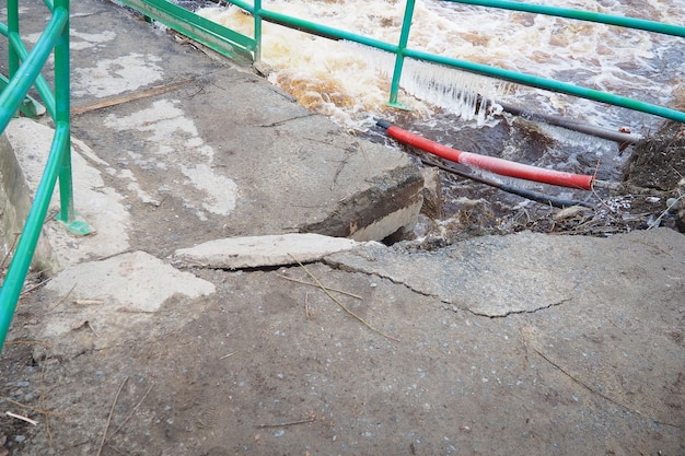 Inundación de primavera Agua corriente en el río Agua ferrosa oscura corre en el arroyo Karelia Río Lososinka en primavera Inundaciones tsunami y cambio climático Puente destruido con tuberías Catástrofe meteorológica