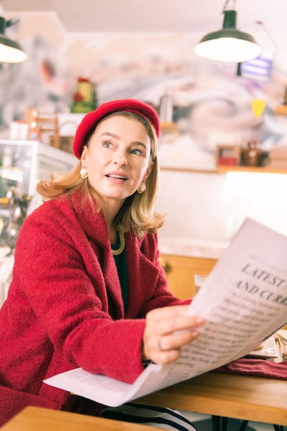 Invadir uma padaria. Mulher de negócios bem-sucedida, elegante e elegante, passando o tempo na padaria lendo jornal