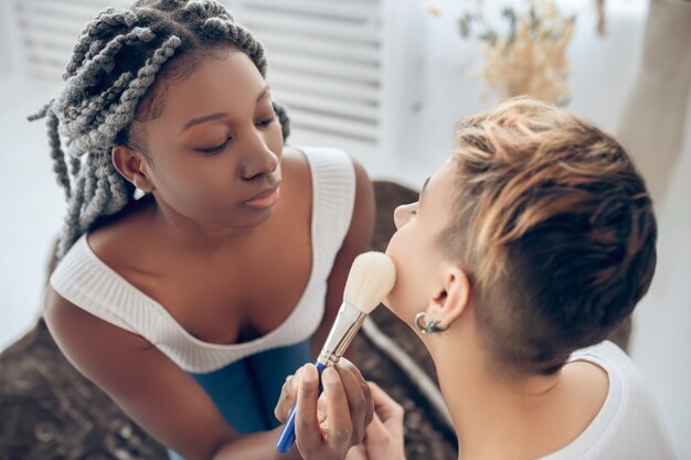 Inventar. Chica afroamericana haciendo maquillaje a su novia