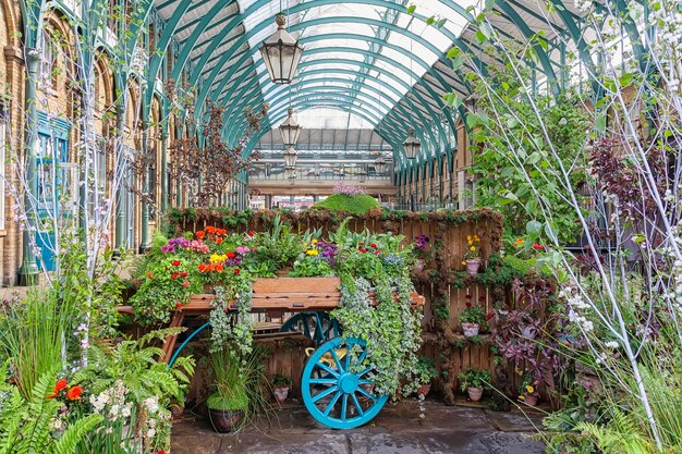 Un invernadero con un carro lleno de flores y plantas.