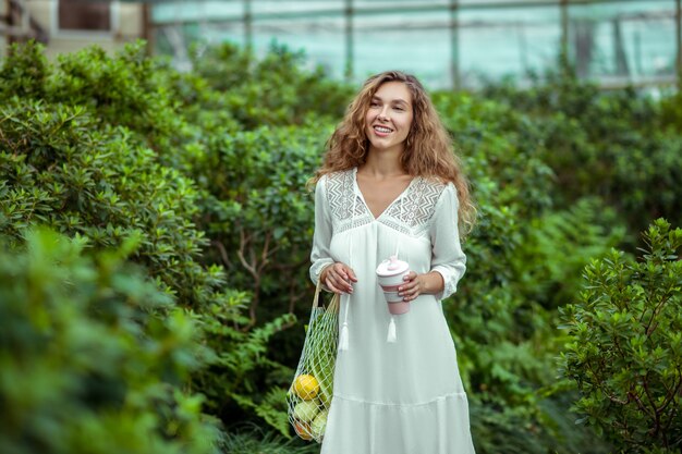 En invernadero. Mujer con vestido blanco con bolsas de verduras en un invernadero