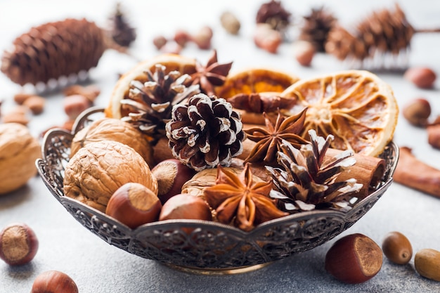 Inverno alimentos ingredientes nozes cones laranjas canela anis estrelado em uma tigela.