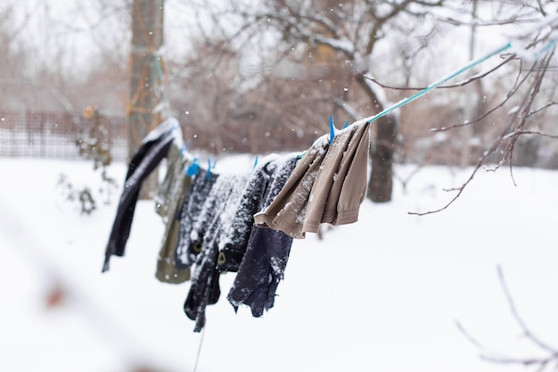 Inverno. As roupas estão secando na rua. Roupas cobertas de neve secam com uma corda apertada.