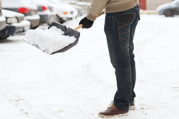 inverno e conceito de limpeza - closeup de homem removendo neve da garagem