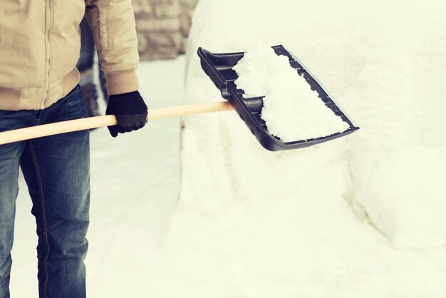 inverno e conceito de limpeza - closeup de homem removendo neve da garagem