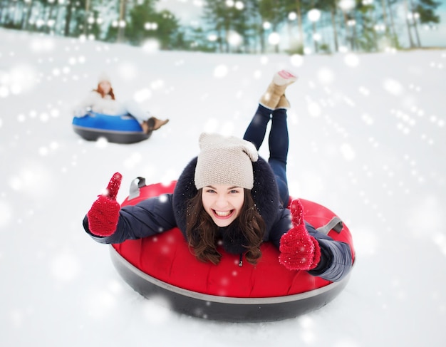 inverno, lazer, esporte, amizade e conceito de pessoas - grupo de amigos felizes deslizando em tubos de neve