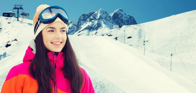 inverno, lazer, esporte e conceito de pessoas - jovem feliz em óculos de esqui sobre neve e fundo de montanha